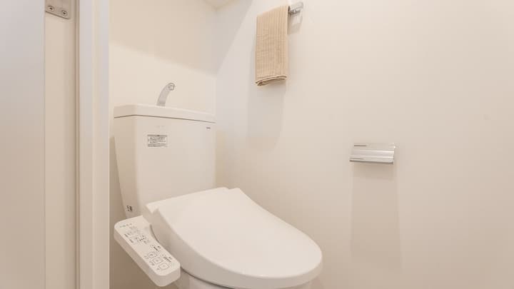 Close-up of a Japanese toilet with an integrated electronic Washlet bidet control panel and a hand-washing basin on top of the tank for water conservation.
