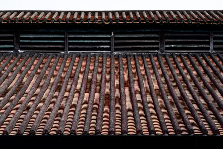 Close-up of a traditional Chinese roof featuring long, dark terracotta and black clay tiles.