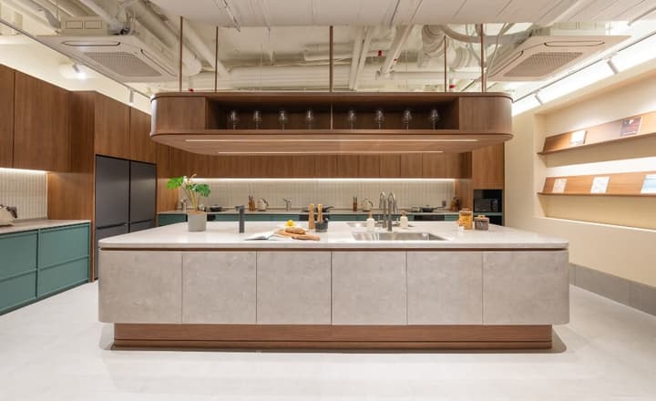 Spacious communal kitchen with a massive stone-top island, wood cabinetry, modern appliances, and overhead storage for glasses.