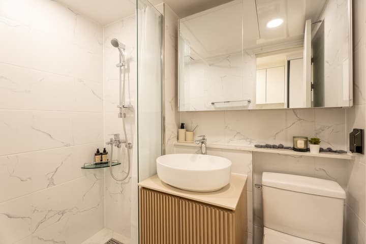 Clean, white kitchen with a marble-effect backsplash, under-cabinet storage, a sink, and a built-in Samsung washer/dryer combo beneath the counter.