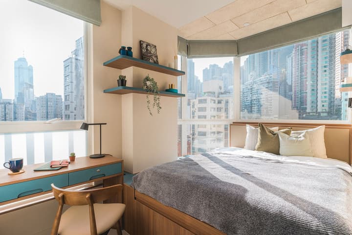 Modern Corner Suite bedroom at Weave Suites – Central West with a queen bed, built-in desk, and panoramic city views from large corner windows.