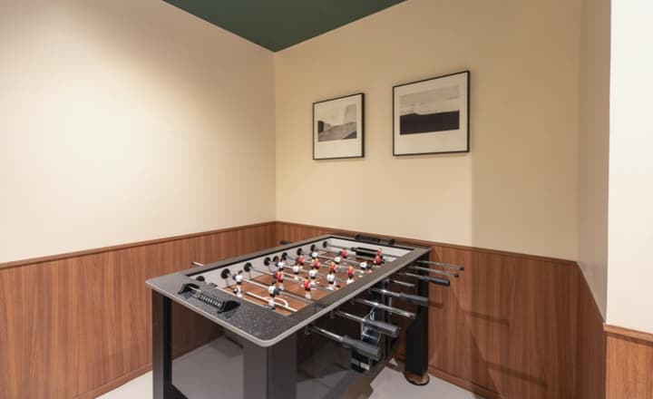Entertainment room corner featuring a foosball table against a wall with lower wood wainscoting and two framed abstract artworks above.
