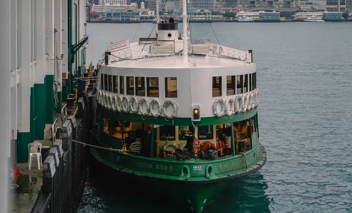 A green and white Star Ferry boat, named 'Meridian Star,' docked at a pier on the water in Victoria Harbour, Hong Kong.