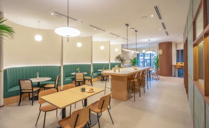 Communal dining area featuring a curved green banquette seating area along one wall and a high dining bar with stools in the center of the room.