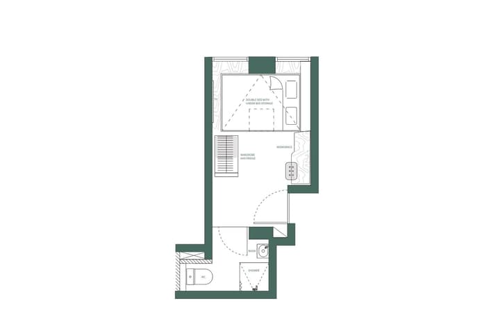 A black and white floor plan diagram for a Studio Queen unit, showing a double bed with under-bed storage, a separate workspace, wardrobe, fridge, and an attached private bathroom with a shower and toilet.