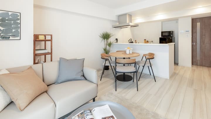 View from the living area toward the dining space, featuring a round wooden table with four modern chairs and a partial view of the minimalist kitchen counter.