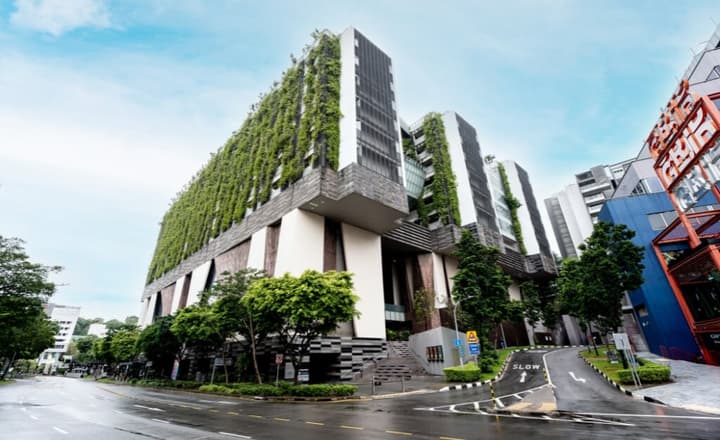 Exterior view of the School of the Arts (SOTA) building in Singapore, featuring a striking modern design with green vertical planting on the facade.
