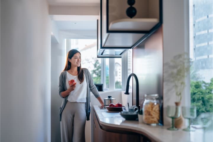 Bright and modern apartment kitchen with ample natural light, a sleek counter, and large windows offering a glimpse of the city outside.