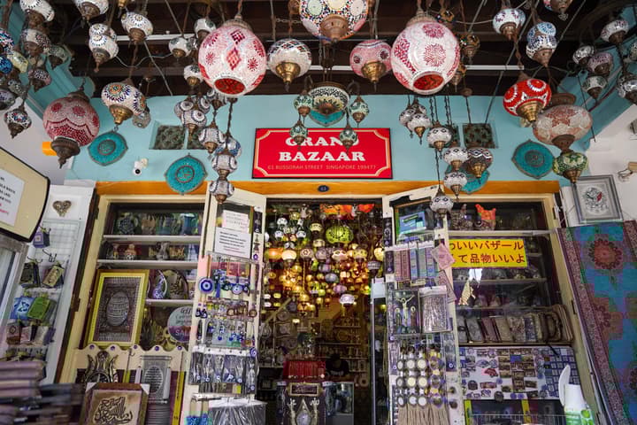 Exterior of the Grand Bazaar shop in Singapore, overflowing with colorful Turkish-style mosaic lanterns hanging from the ceiling and various souvenirs.
