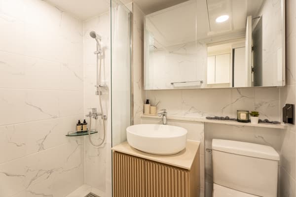 Clean, white kitchen with a marble-effect backsplash, under-cabinet storage, a sink, and a built-in Samsung washer/dryer combo beneath the counter.
