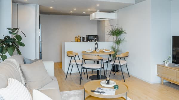 Open-concept view of the living and dining area, featuring a round dining table with four chairs, set against a counter that separates it from the compact kitchen.