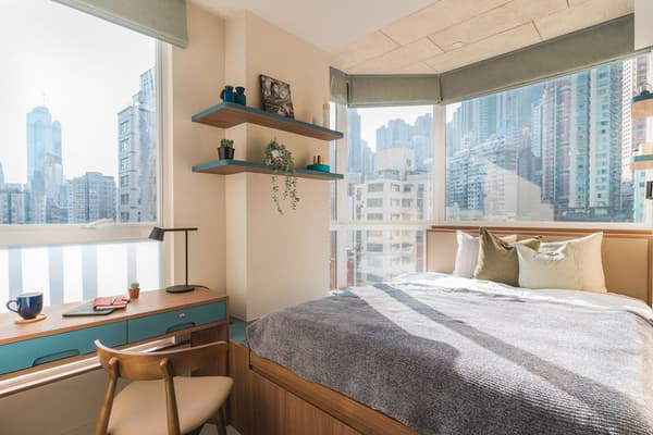 Modern Corner Suite bedroom at Weave Suites – Central West with a queen bed, built-in desk, and panoramic city views from large corner windows.