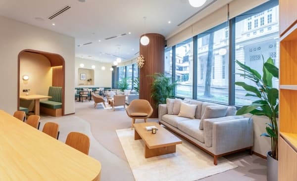 Ground floor lounge and social area featuring a long communal table, a comfortable sofa seating area, and large windows overlooking the exterior streetscape.