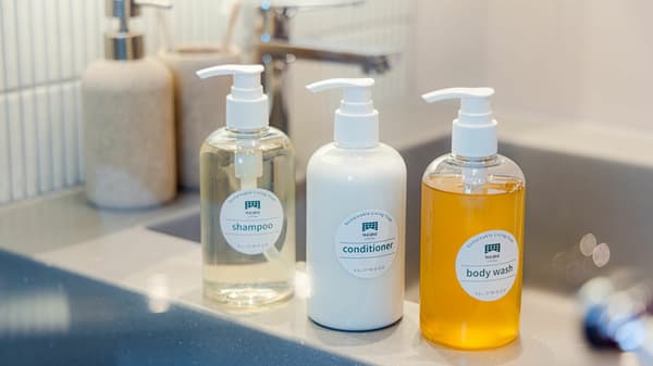 Close-up of three pump bottles labeled 'shampoo,' 'conditioner,' and 'body wash' from Slowood, sitting on a bathroom counter.