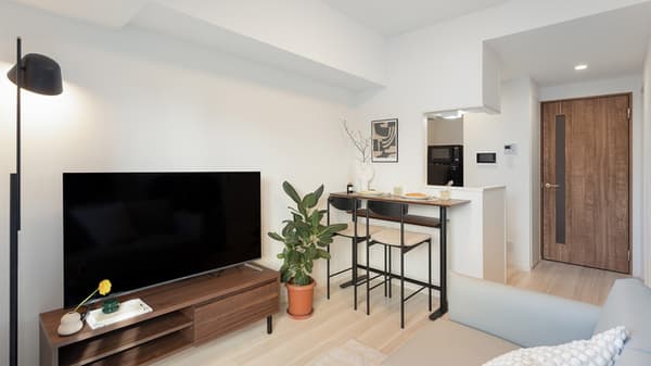 Bright, open-plan living and dining area with a two-seater counter-height dining bar and a large TV on a wooden console.