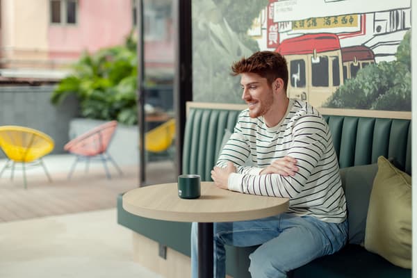 FileResident enjoying a coffee in the cozy lounge at Weave Studios – Kai Tak in Hong Kong, featuring modern seating, colorful outdoor chairs, and a relaxed atmosphere.